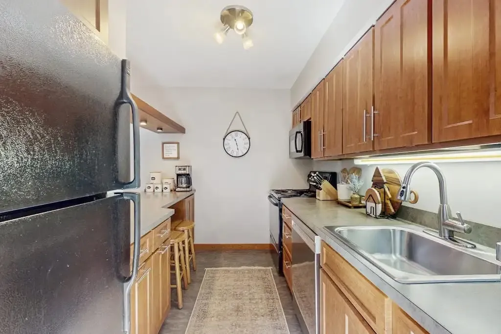 Galley kitchen with a black refrigerator, gas range, and breakfast bar seating