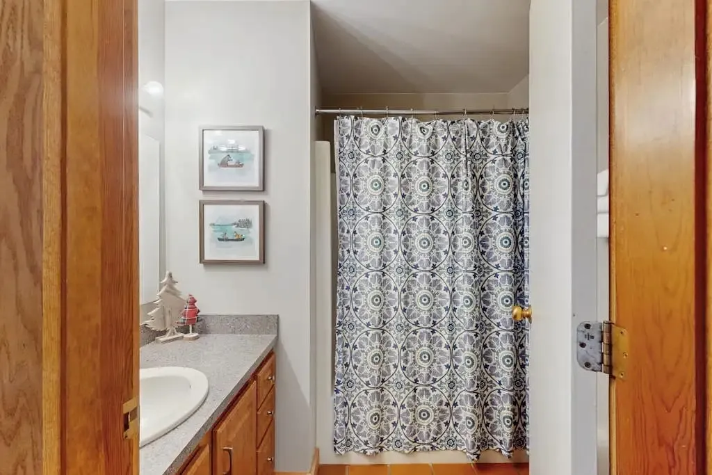 Second bathroom shower with a patterned curtain and nautical wall art
